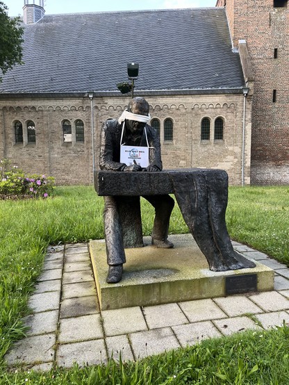 Een standbeeld van Simon Vestdijk in Doorn. Het standbeeld staat voor een kerk. Het beeld is geblinddoekt en heeft een bord om de nek hangen met de tekst 